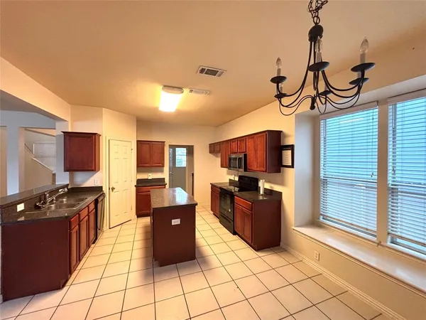 a kitchen with stainless steel appliances a stove top oven a sink a counter top space and cabinets