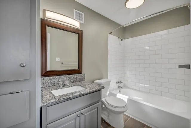 a bathroom with a granite countertop sink toilet mirror and bathtub