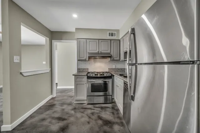 a kitchen with a refrigerator a stove top oven and cabinets