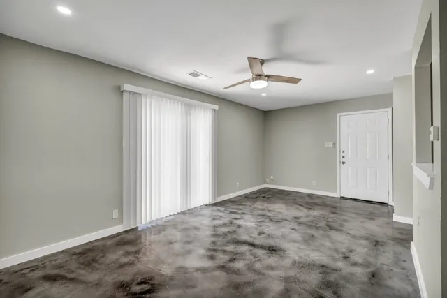 an empty room with ceiling fan and window