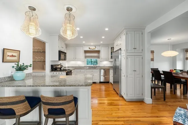 a kitchen with stainless steel appliances kitchen island granite countertop a table chairs sink and cabinets