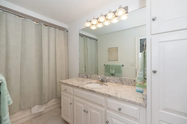 a bathroom with a granite countertop sink a mirror and a shower