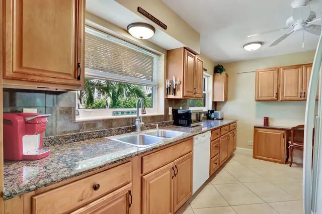 a kitchen with granite countertop a sink stainless steel appliances white cabinets and a window