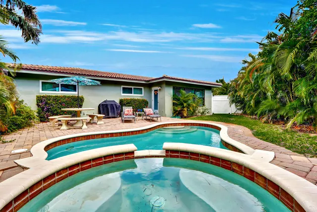 a view of swimming pool with lawn chairs and plants
