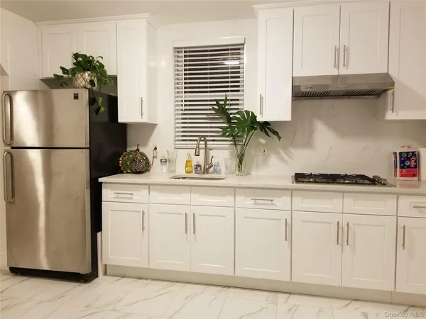 a kitchen with white cabinets and refrigerator