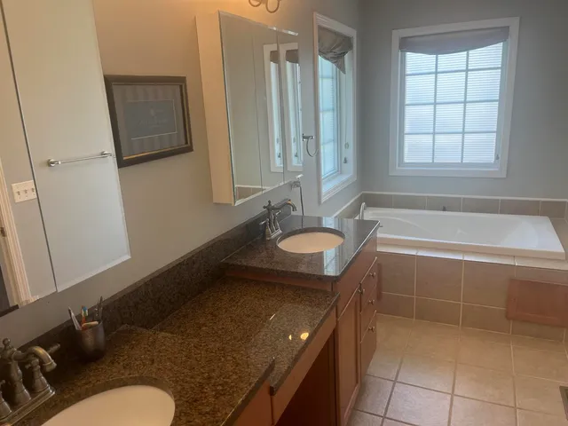 a bathroom with a granite countertop sink a mirror and a bathtub