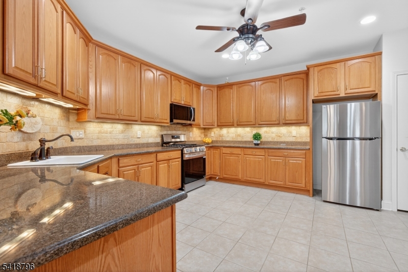 9210 Ravenscroft Road Clifton, NJ 07013 - Photo 8 of 18 a kitchen with stainless steel appliances granite countertop a sink refrigerator stove and microwave