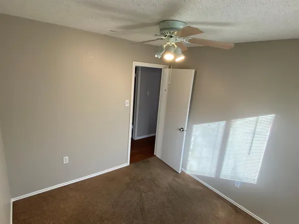 an empty room with chandelier fan and windows