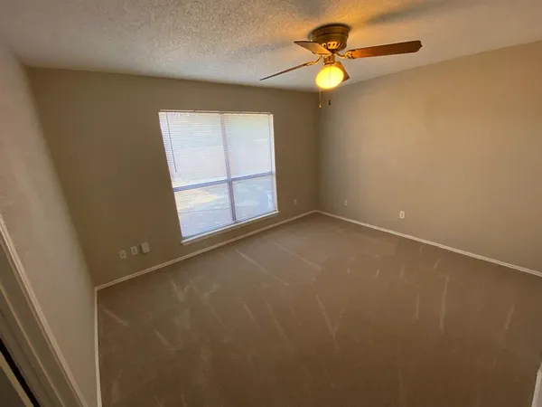 an empty room with windows and fan