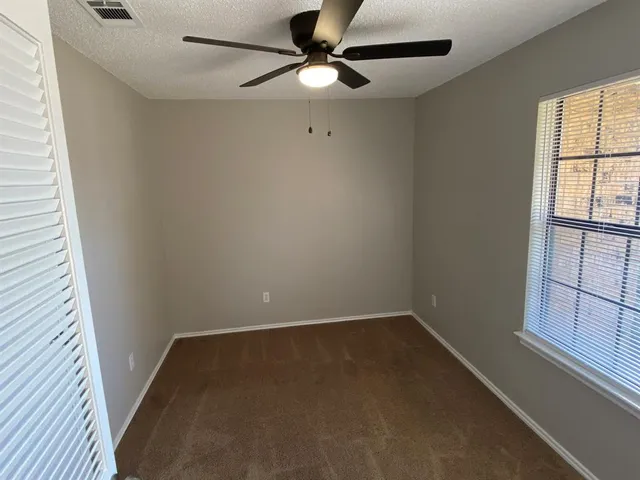 an empty room with windows and fan