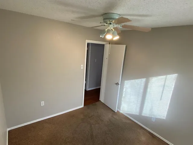 an empty room with chandelier fan and windows