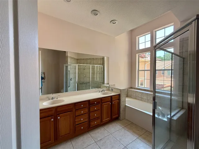 a spacious bathroom with a granite countertop tub sink shower and mirror