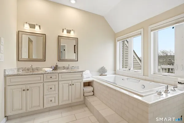 a spacious bathroom with a double vanity sink large mirror and a bathtub