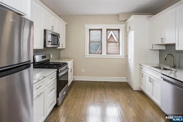 a kitchen with granite countertop a refrigerator stove top oven and sink