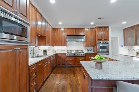 a large kitchen with stainless steel appliances granite countertop a stove a sink and a microwave