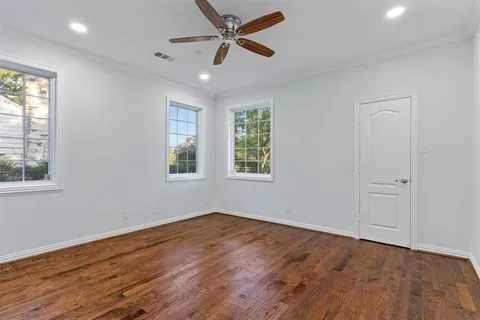 an empty room with wooden floor ceiling fan and windows