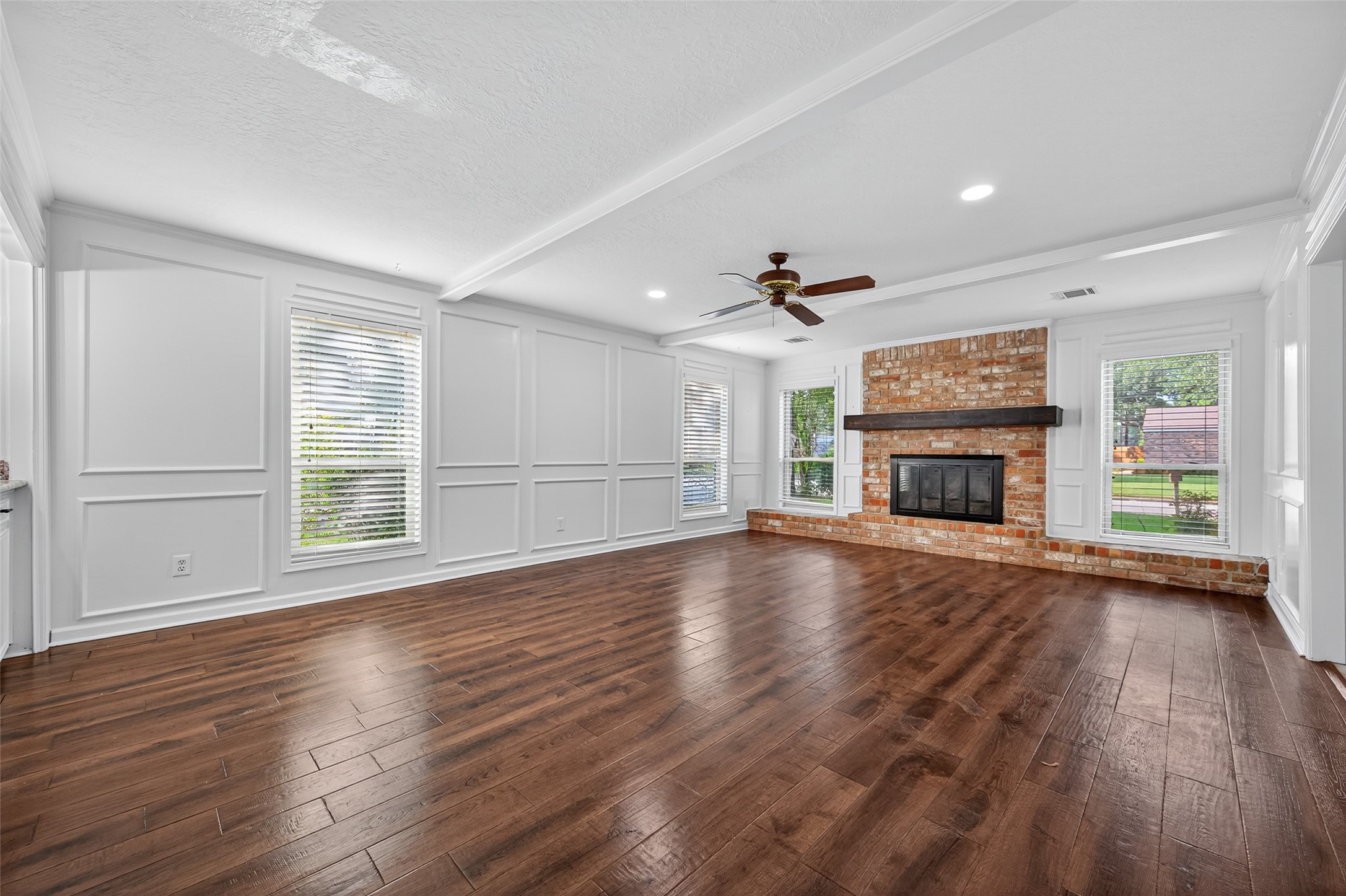 202 Laura Lane Conroe, TX 77385 - Photo 6 of 31 an empty room with wooden floor fireplace and windows