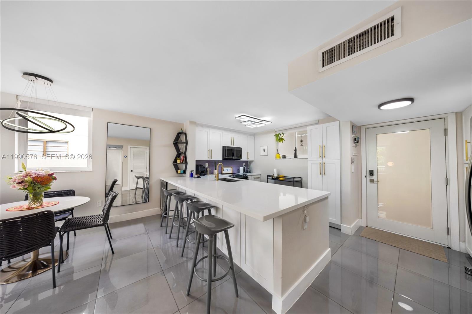 1665 Bay Road, Unit 221 Miami Beach, FL 33139 - Photo 10 of 33 a kitchen with a dining table chairs and white cabinets