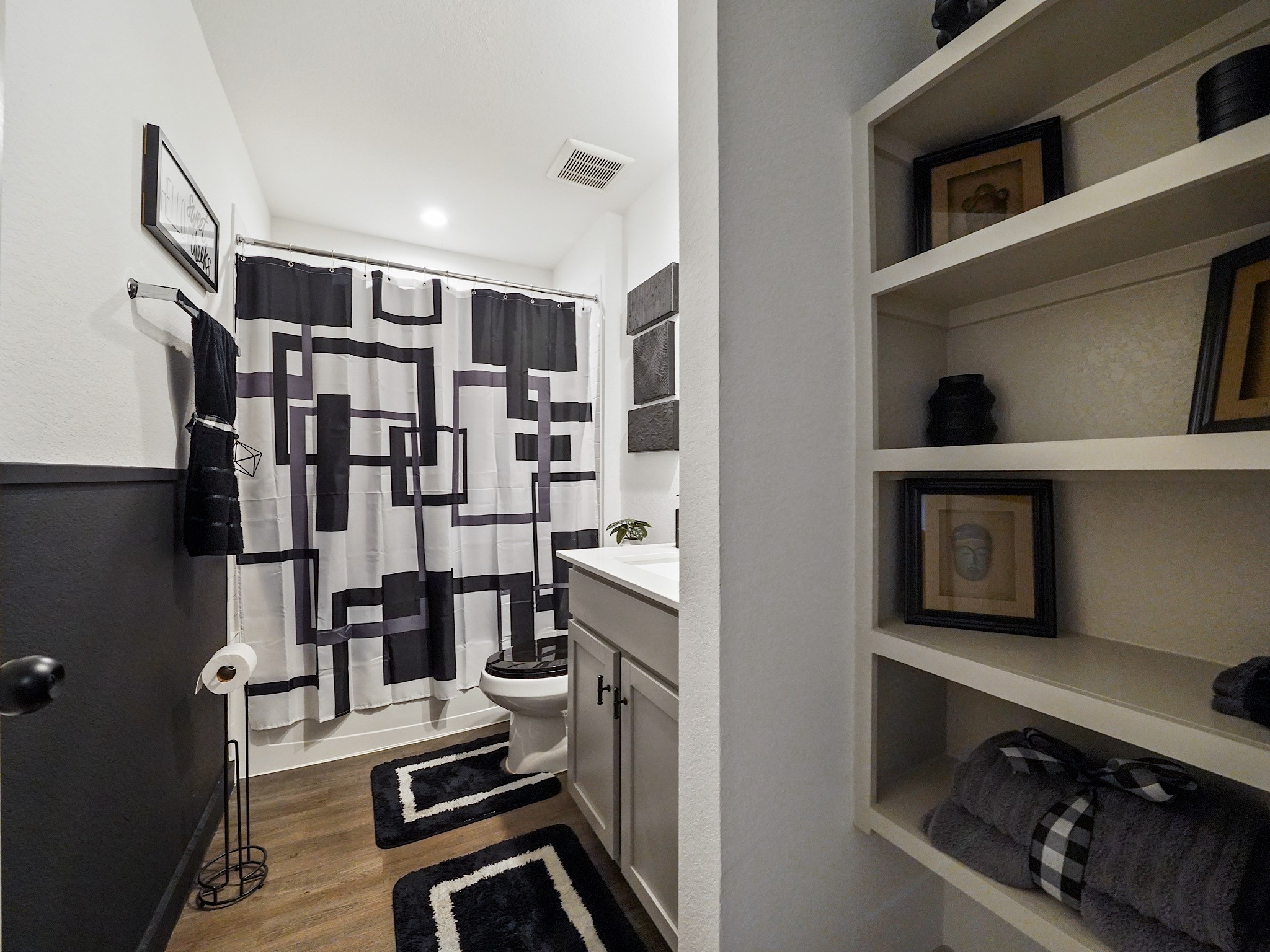 7823 Cattlewood Pass Rosharon, TX 77583 - Photo 5 of 17 Bathroom has open shelving for storage, a vanity with a sleek countertop, and wood-style flooring, creating a stylish and functional space.