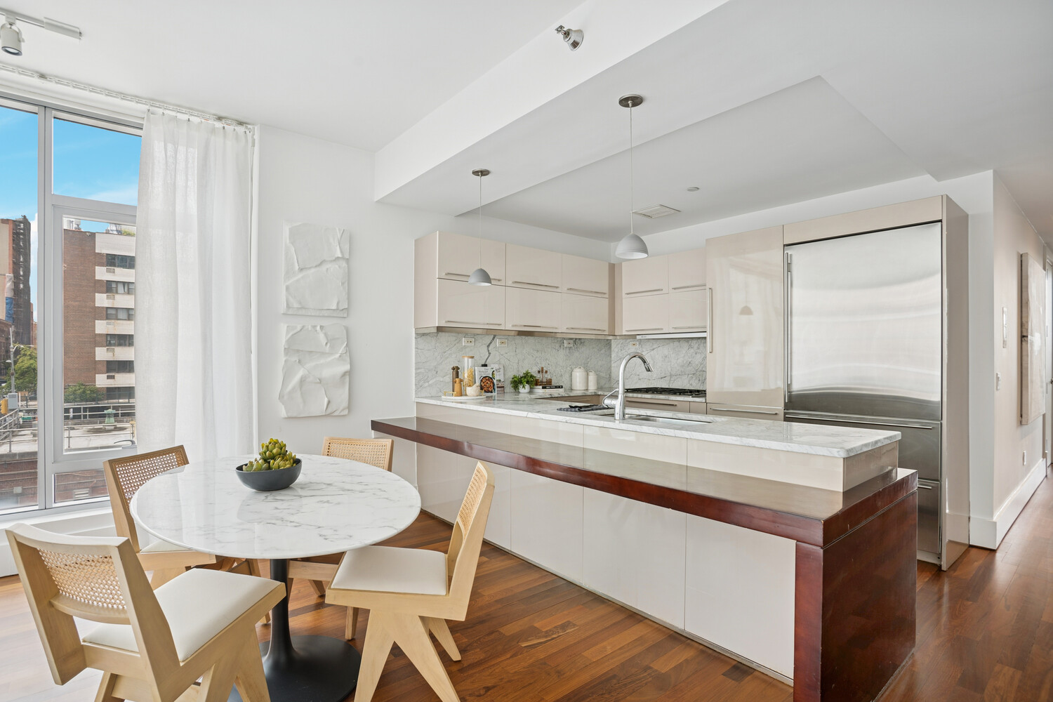 165 West 18th Street, Unit 3C Manhattan, NY 10011 - Photo 3 of 12 a kitchen with stainless steel appliances granite countertop a dining table chairs and white cabinets