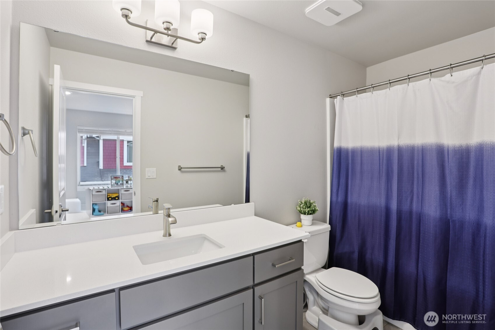 12006 Northeast 194th Drive, Unit E Bothell, WA 98011 - Photo 16 of 25 a bathroom with a sink a toilet a mirror and shower curtain