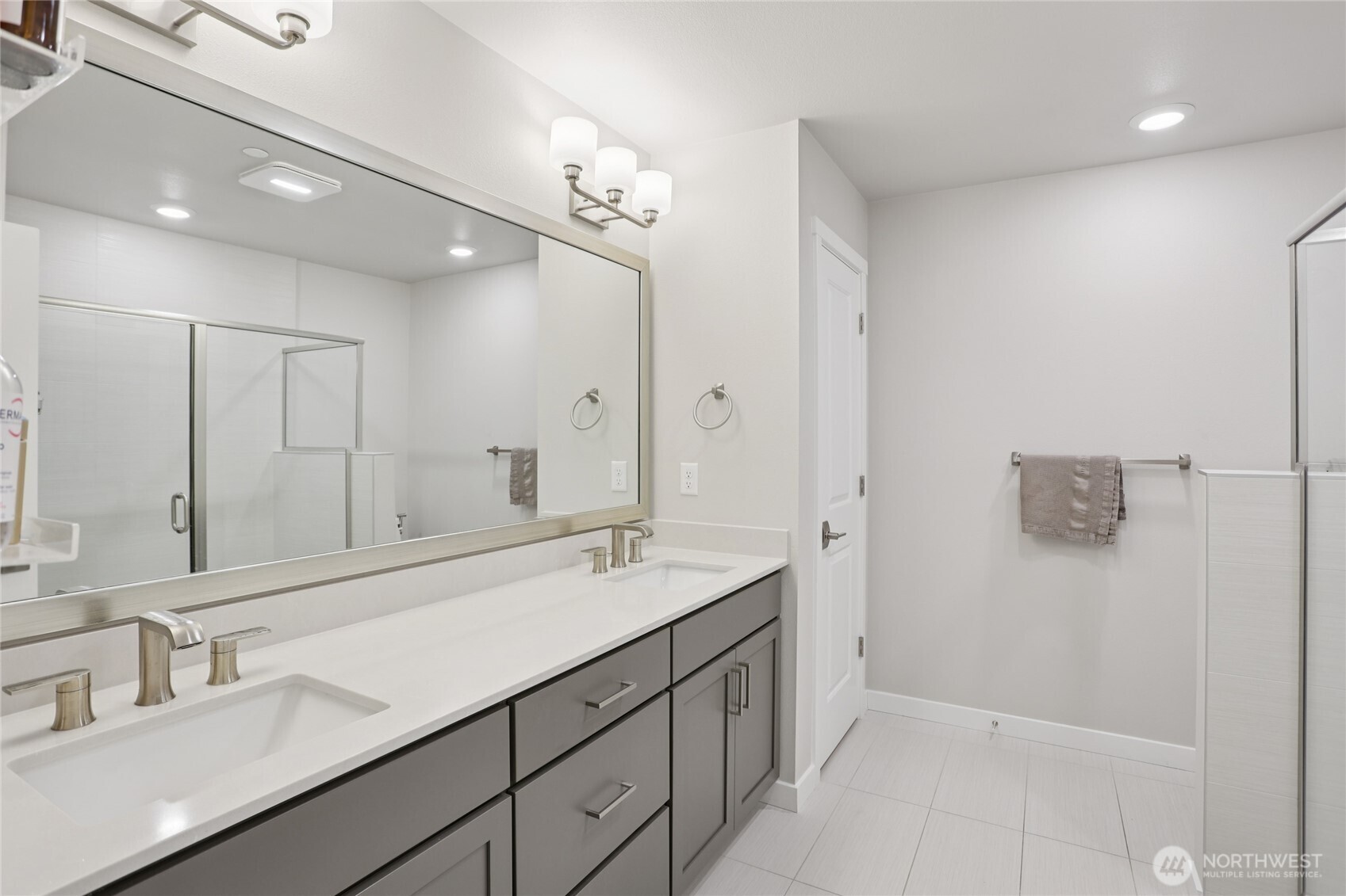 12006 Northeast 194th Drive, Unit E Bothell, WA 98011 - Photo 21 of 25 a bathroom with a double vanity sink a mirror and a shower