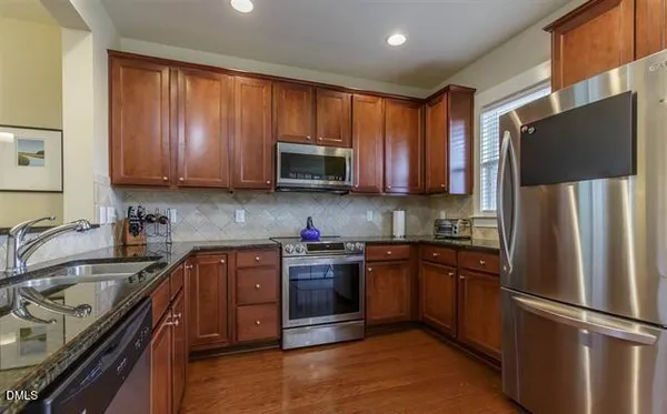 a kitchen with stainless steel appliances granite countertop a refrigerator stove top oven and sink