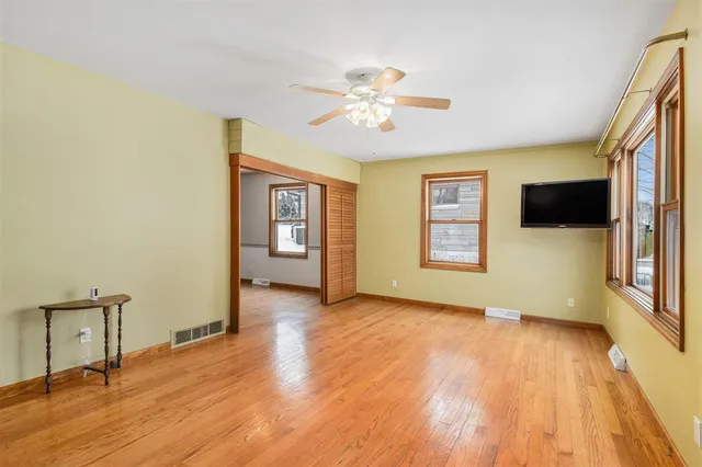 a view of an empty room with a window and wooden floor