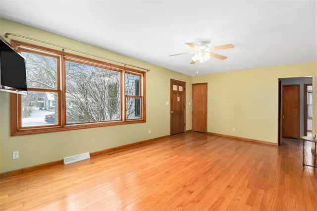 a view of an empty room with a window and wooden floor