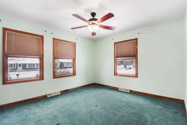 an empty room with windows and ceiling fan