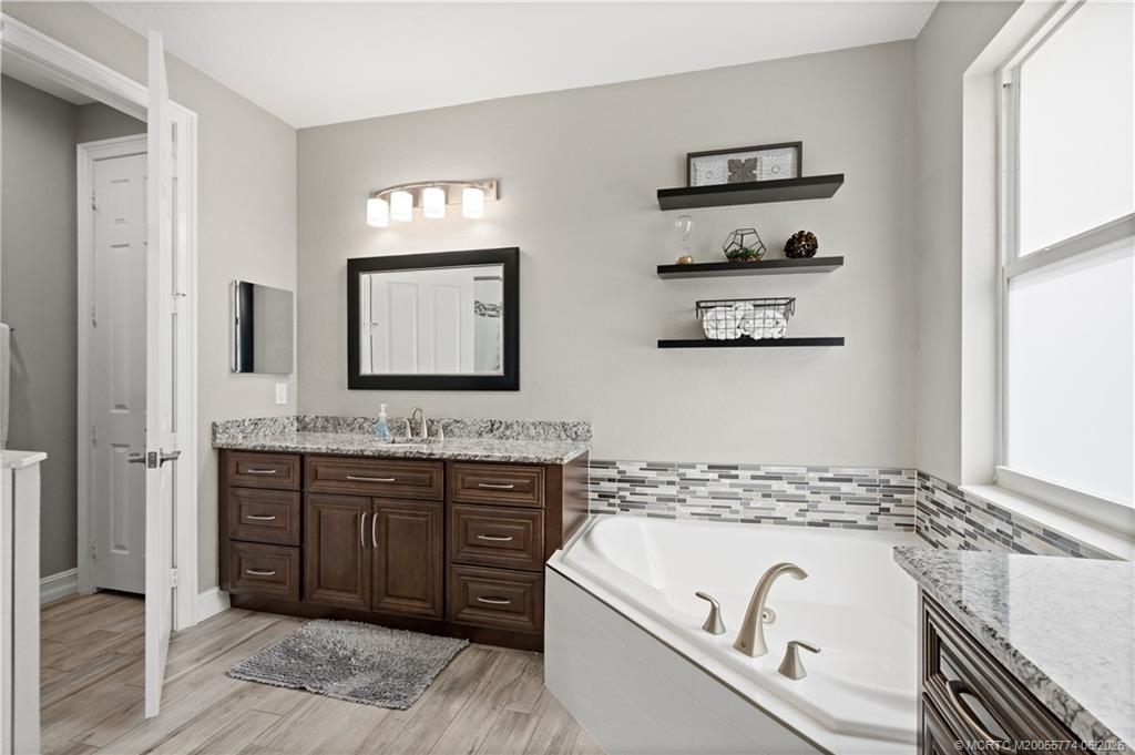 1268 Southeast Kirk Street Stuart, FL 34997 - Photo 35 of 63 a spacious bathroom with a granite countertop tub sink and mirror