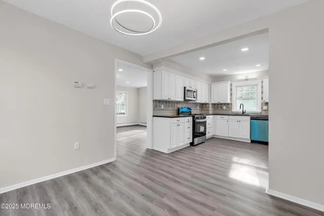 a kitchen with stainless steel appliances granite countertop a stove a sink and white cabinets