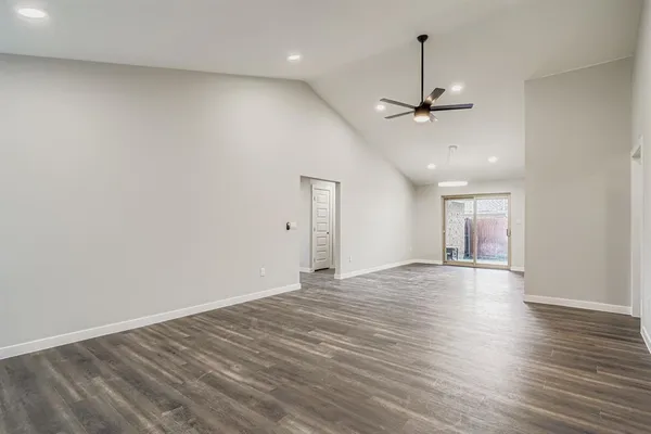 an empty room with wooden floor ceiling fan and window