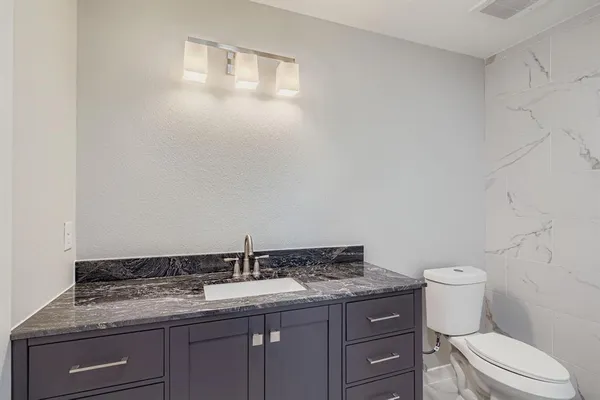 a bathroom with a granite countertop toilet and a sink