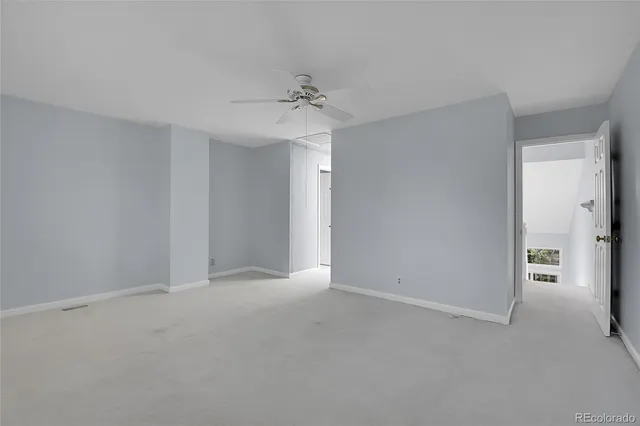 a view of an empty room and chandelier fan