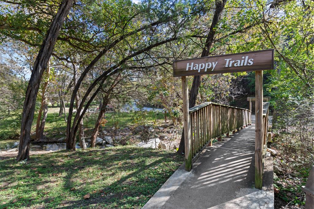 2210 Red Fox Road Austin, TX 78734 - Photo 40 of 40 A charming wooden bridge spans a tranquil creek, leading to inviting walking paths under a canopy of mature trees.