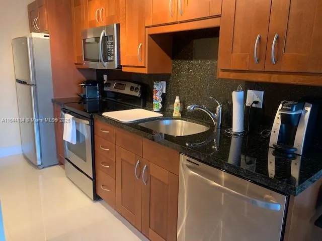 a kitchen with granite countertop a sink and a refrigerator