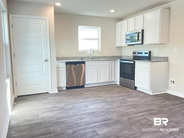 1024 South Bay Street Foley, AL 36535 - Photo 7 of 28 Kitchen with stainless steel appliances, light hardwood / wood-style floors, white cabinets, and light stone countertops