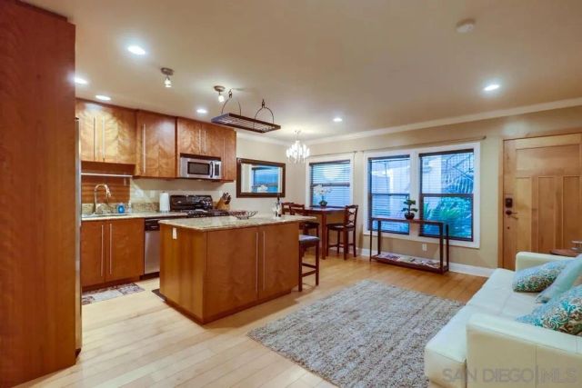 a living room with stainless steel appliances granite countertop furniture and a wooden floor