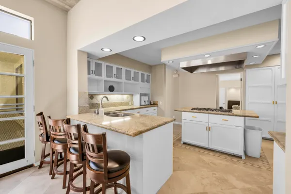 a kitchen with kitchen island a stove a sink a refrigerator and white cabinets with wooden floor