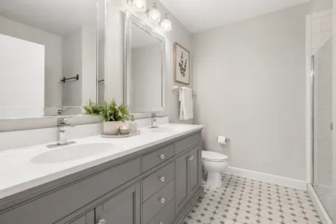 a bathroom with a double vanity sink toilet and a mirror