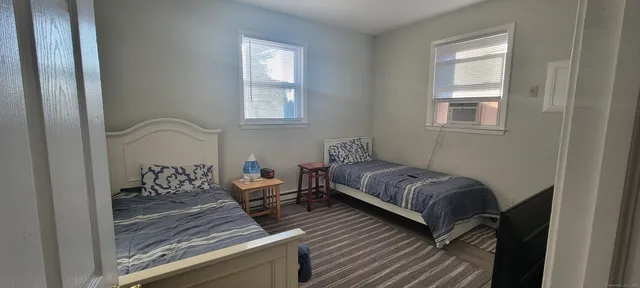 a bed sitting in a bedroom next to a window and chair