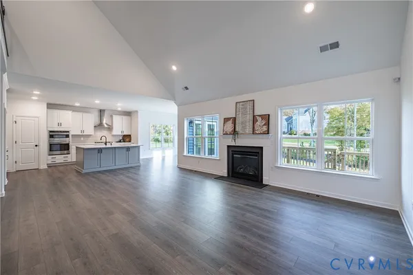 an empty room with wooden floor and a kitchen