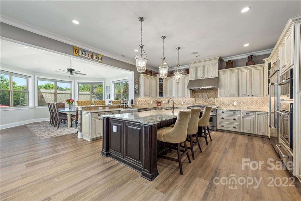 4040 Flowering Peach Road Marvin, NC 28173 - Photo 36 of 38 a kitchen with stainless steel appliances granite countertop a table chairs stove and a wooden floors