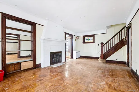 a view of an empty room with wooden floor fireplace and a window