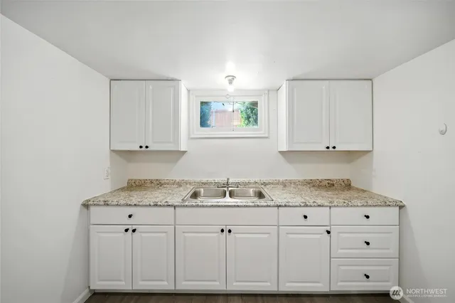 a kitchen with granite countertop white cabinets and sink