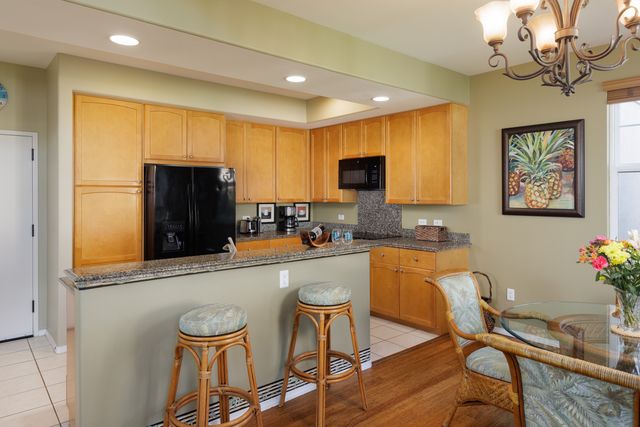 a kitchen with stainless steel appliances granite countertop a refrigerator a sink a stove a dining table and chairs with wooden floor