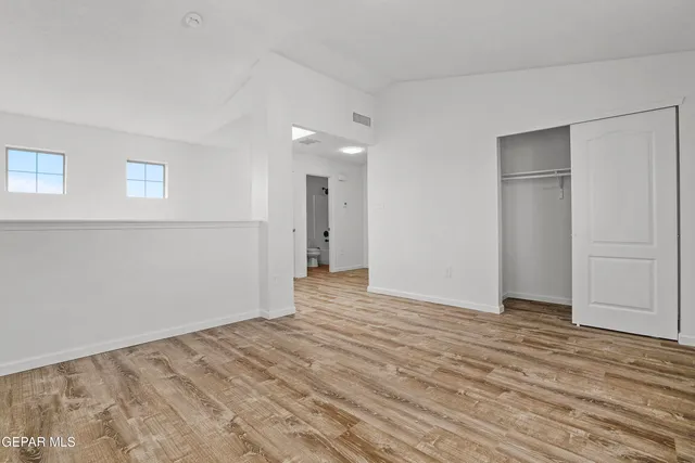 a view of an empty room with wooden floor and closet