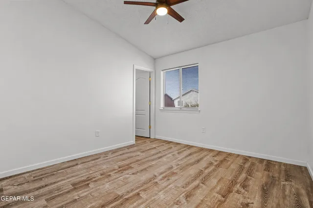 an empty room with wooden floor fan and a ceiling fan