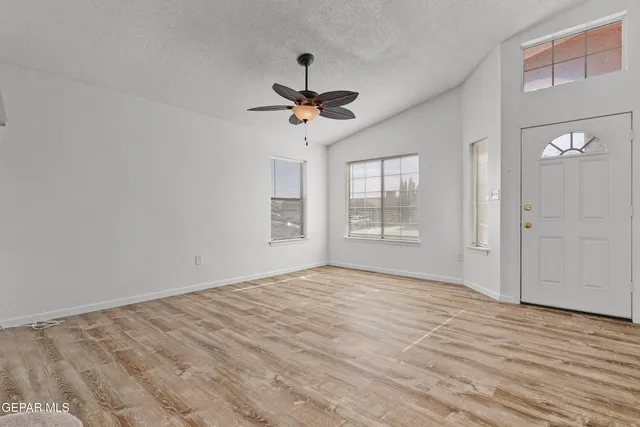 a view of empty room with wooden floor and fan